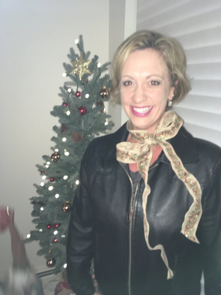 Jena smiling by Christmas tree with ribbon around neck
